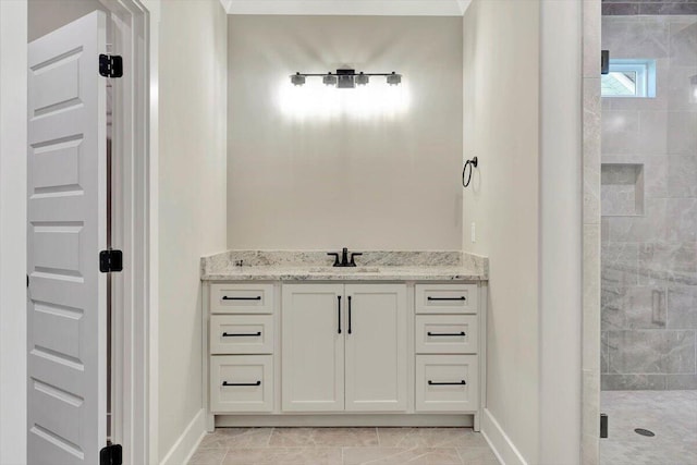 bathroom featuring tile patterned flooring, a tile shower, and vanity