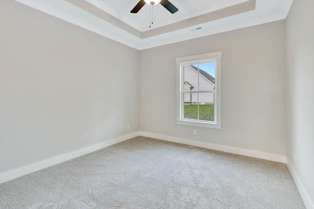 unfurnished room featuring a raised ceiling, ceiling fan, and carpet