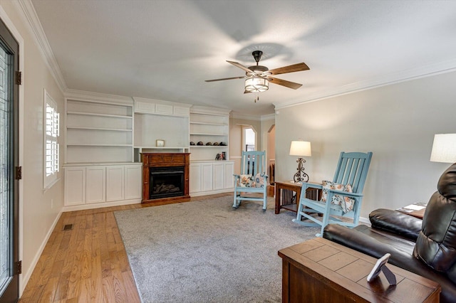 unfurnished living room featuring ceiling fan, ornamental molding, and light wood-type flooring