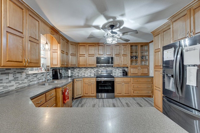 kitchen featuring ceiling fan, stainless steel appliances, sink, and backsplash