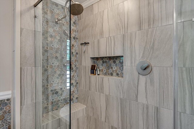 bathroom with ornamental molding and a tile shower