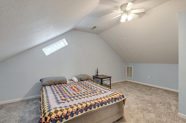 carpeted bedroom with a textured ceiling, ceiling fan, and lofted ceiling with skylight