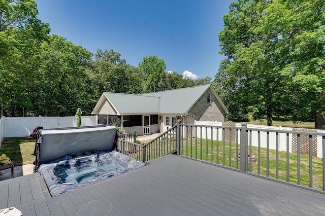 wooden deck with a lawn and a covered hot tub