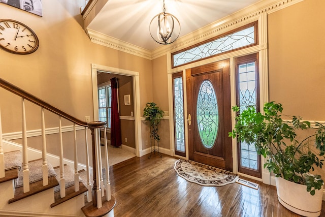 foyer entrance with stairway, baseboards, wood-type flooring, and a chandelier