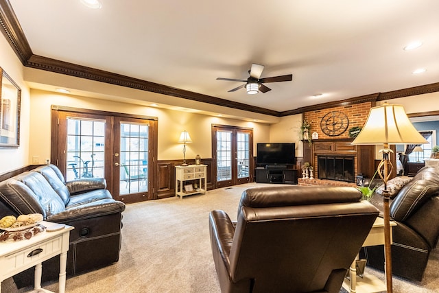 living area with wainscoting, french doors, light colored carpet, and ornamental molding