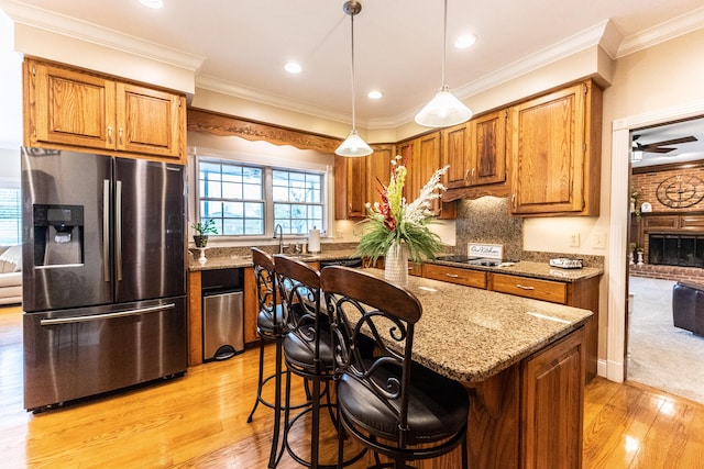 kitchen with brown cabinetry, light stone countertops, stainless steel fridge with ice dispenser, and crown molding