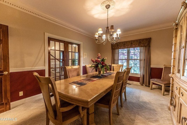 dining space featuring a wainscoted wall, a notable chandelier, french doors, crown molding, and light colored carpet