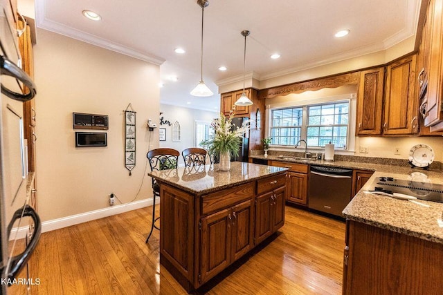 kitchen with light wood-style flooring, a sink, stainless steel dishwasher, crown molding, and a kitchen bar