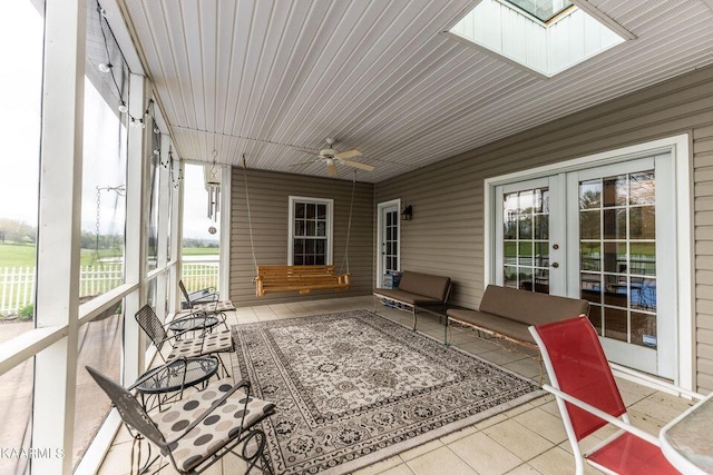 sunroom / solarium with a ceiling fan, a skylight, and french doors