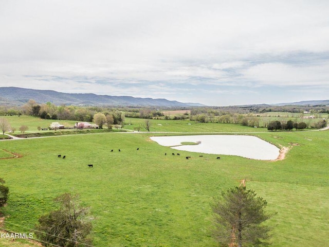 exterior space featuring a rural view, a lawn, and a mountain view