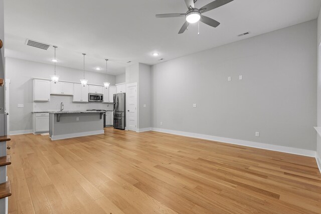 unfurnished living room featuring ceiling fan, sink, and light hardwood / wood-style flooring