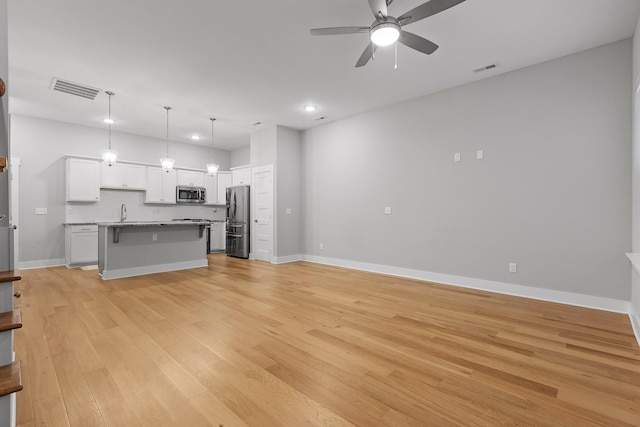 kitchen with a ceiling fan, light wood-style flooring, stainless steel appliances, visible vents, and white cabinets