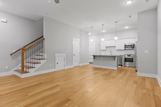 unfurnished living room featuring ceiling fan, sink, and light hardwood / wood-style flooring