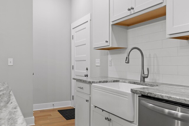 kitchen with dishwasher, light stone countertops, light hardwood / wood-style floors, white cabinetry, and tasteful backsplash