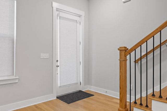 entrance foyer featuring baseboards, wood finished floors, and stairway