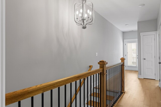 hallway with an inviting chandelier and light hardwood / wood-style floors