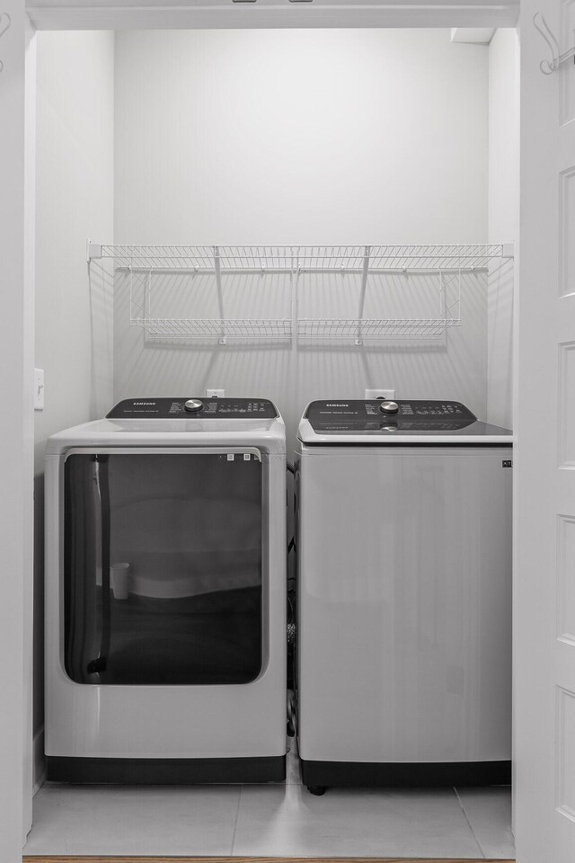 clothes washing area with independent washer and dryer and light tile patterned flooring