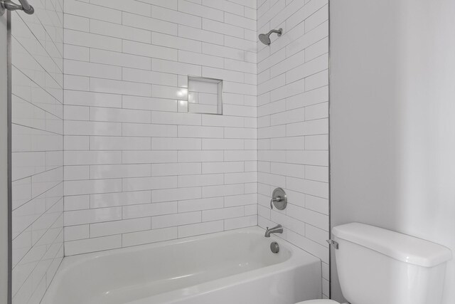 bathroom featuring toilet and tiled shower / bath