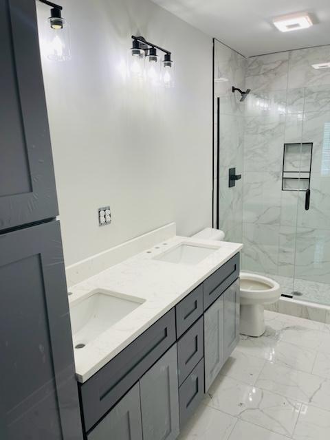 bathroom featuring toilet, an enclosed shower, and vanity