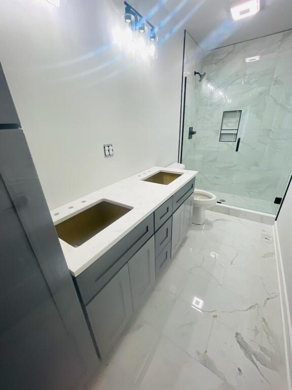 bathroom featuring vanity, toilet, and tiled shower