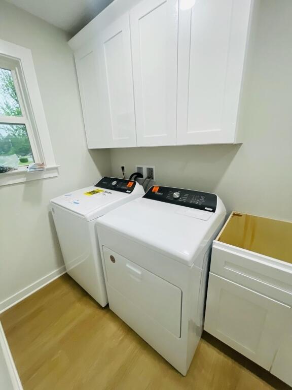 laundry area with cabinets, washer and clothes dryer, and light hardwood / wood-style floors