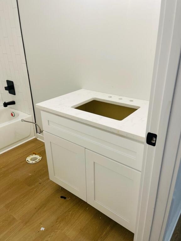 bathroom with hardwood / wood-style flooring, shower / bathing tub combination, and vanity