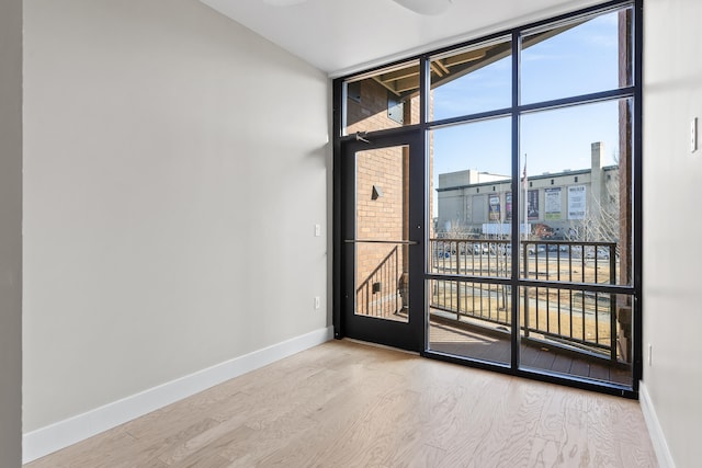 spare room with plenty of natural light, expansive windows, and wood-type flooring