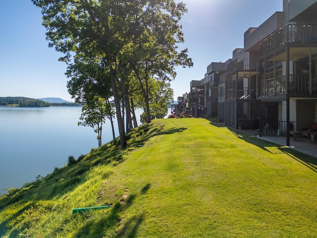 surrounding community featuring a water and mountain view and a lawn