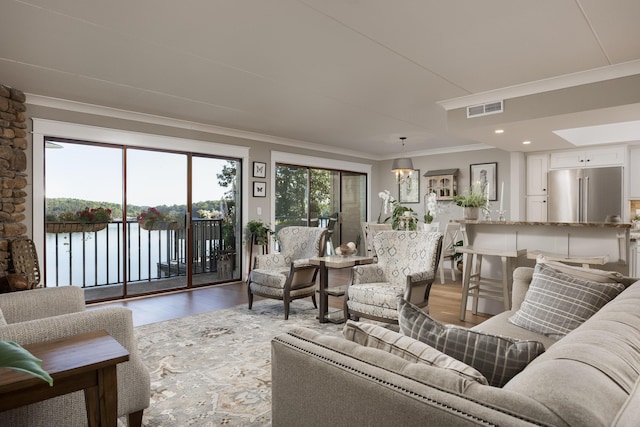 living room featuring crown molding, hardwood / wood-style floors, and a water view