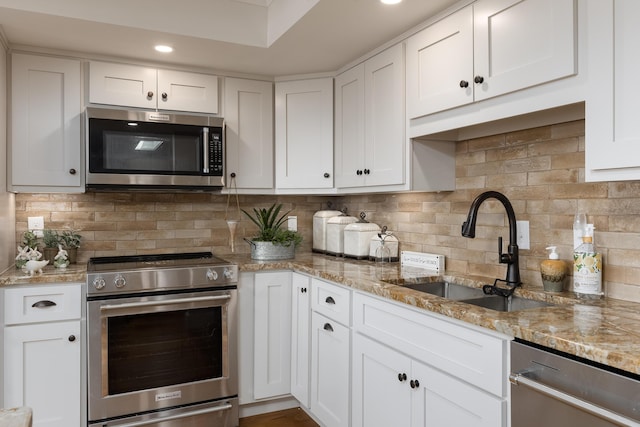 kitchen with white cabinetry, a sink, appliances with stainless steel finishes, and decorative backsplash