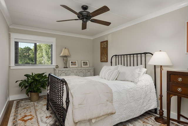 bedroom with baseboards, ornamental molding, wood finished floors, and a ceiling fan