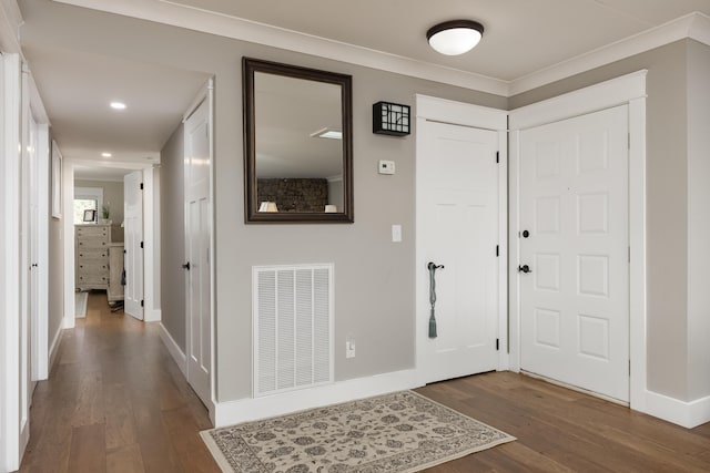 entrance foyer with dark wood finished floors, ornamental molding, baseboards, and visible vents