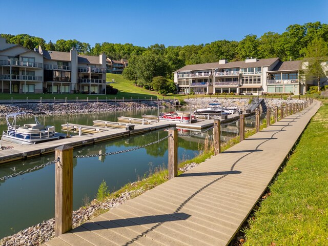 view of dock featuring a balcony, a water view, and a yard