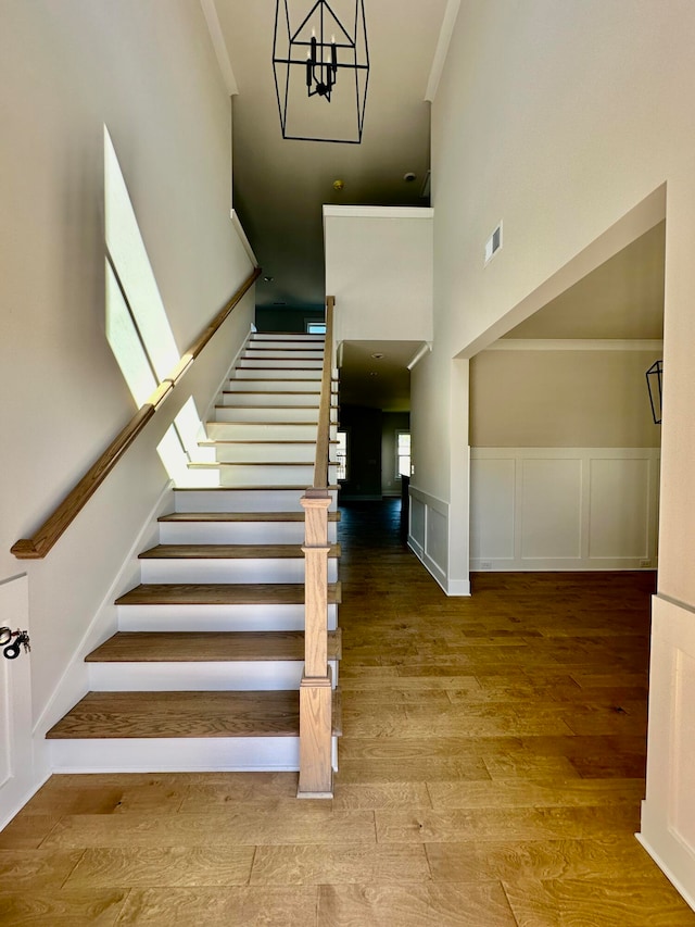 stairs featuring a chandelier, wood-type flooring, and a high ceiling