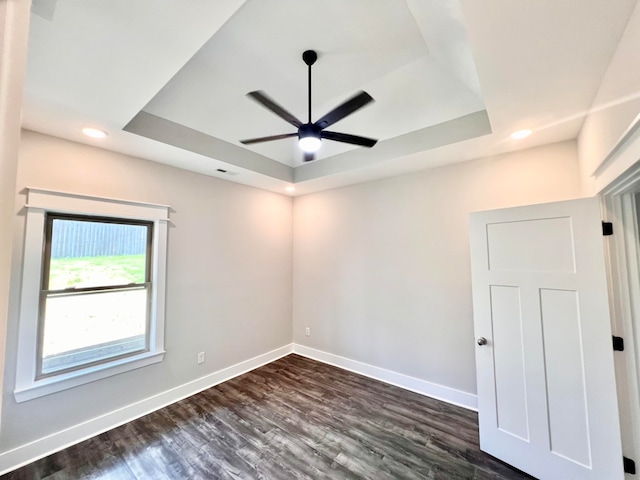 unfurnished room with a tray ceiling, ceiling fan, and dark hardwood / wood-style floors