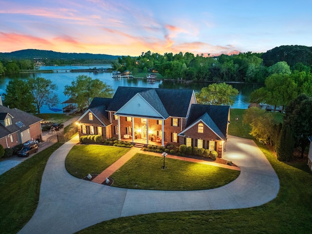 view of front of property with a lawn and a water view