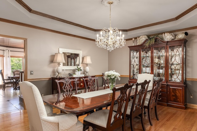 dining space with a chandelier, crown molding, and light hardwood / wood-style flooring