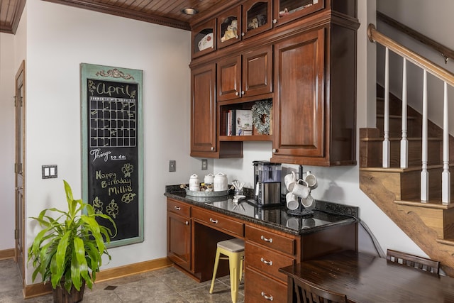 kitchen featuring ornamental molding, dark stone counters, and built in desk