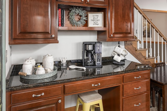 kitchen featuring dark stone countertops, built in desk, and a breakfast bar area