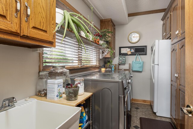 washroom featuring a textured ceiling, washing machine and dryer, sink, and light tile patterned floors