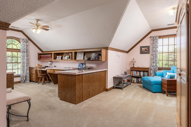 office featuring built in desk, light colored carpet, lofted ceiling, ceiling fan, and a textured ceiling