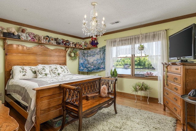 bedroom with light hardwood / wood-style flooring, ornamental molding, a chandelier, and a textured ceiling