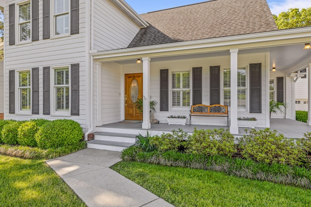 view of exterior entry with a porch and a yard