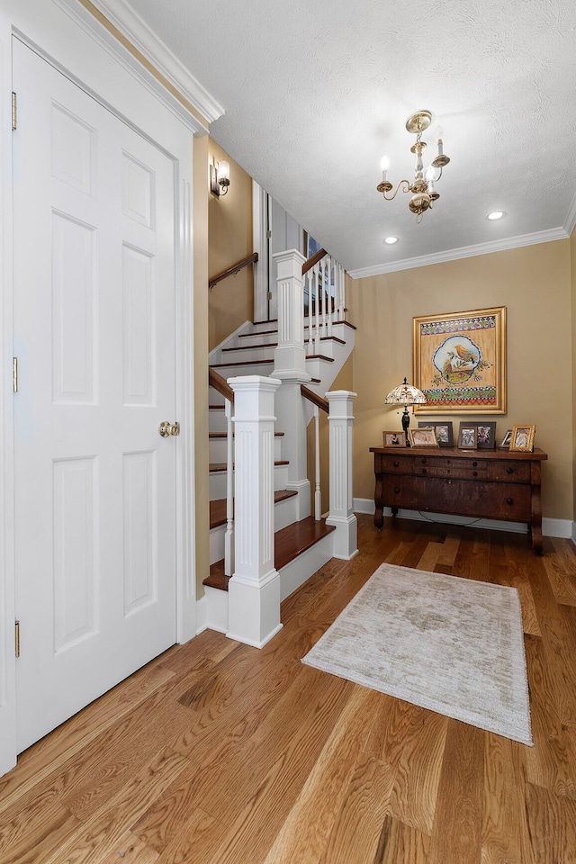 interior space with crown molding, a textured ceiling, hardwood / wood-style flooring, and a chandelier