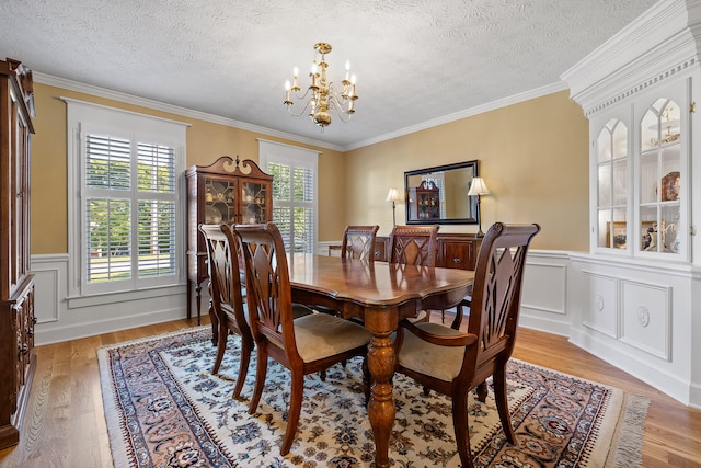 dining area with crown molding, a textured ceiling, light hardwood / wood-style flooring, and an inviting chandelier