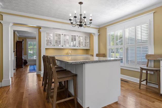 kitchen with a textured ceiling, crown molding, and hardwood / wood-style flooring