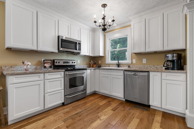 kitchen featuring white cabinets, stainless steel appliances, sink, and light hardwood / wood-style floors