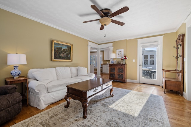 living room with light hardwood / wood-style floors, ceiling fan, decorative columns, and ornamental molding