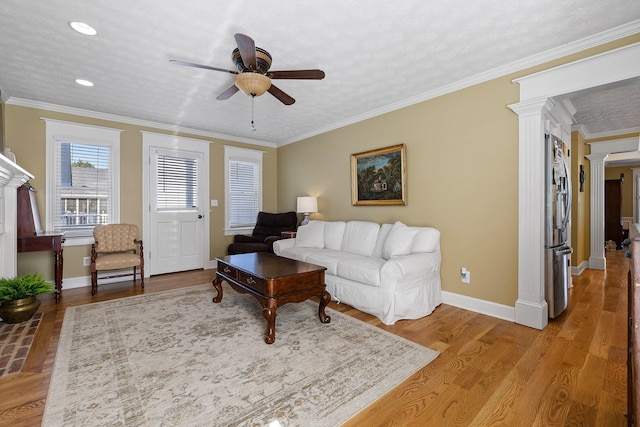 living room with light wood-type flooring, ornamental molding, a textured ceiling, decorative columns, and ceiling fan