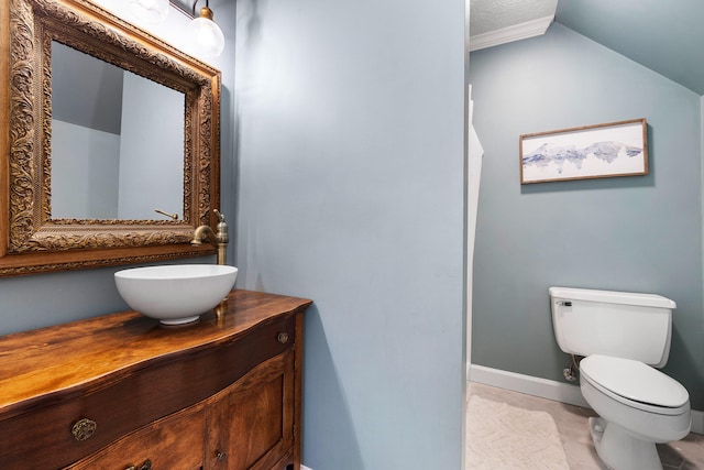 bathroom featuring tile patterned floors, vanity, toilet, and vaulted ceiling